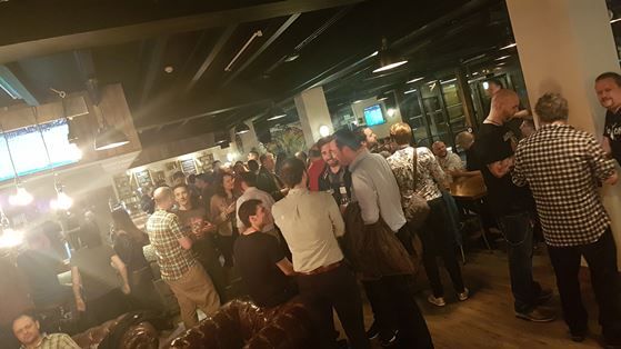 Image of a group of attendees at IWMW eating and drinking at an afterparty